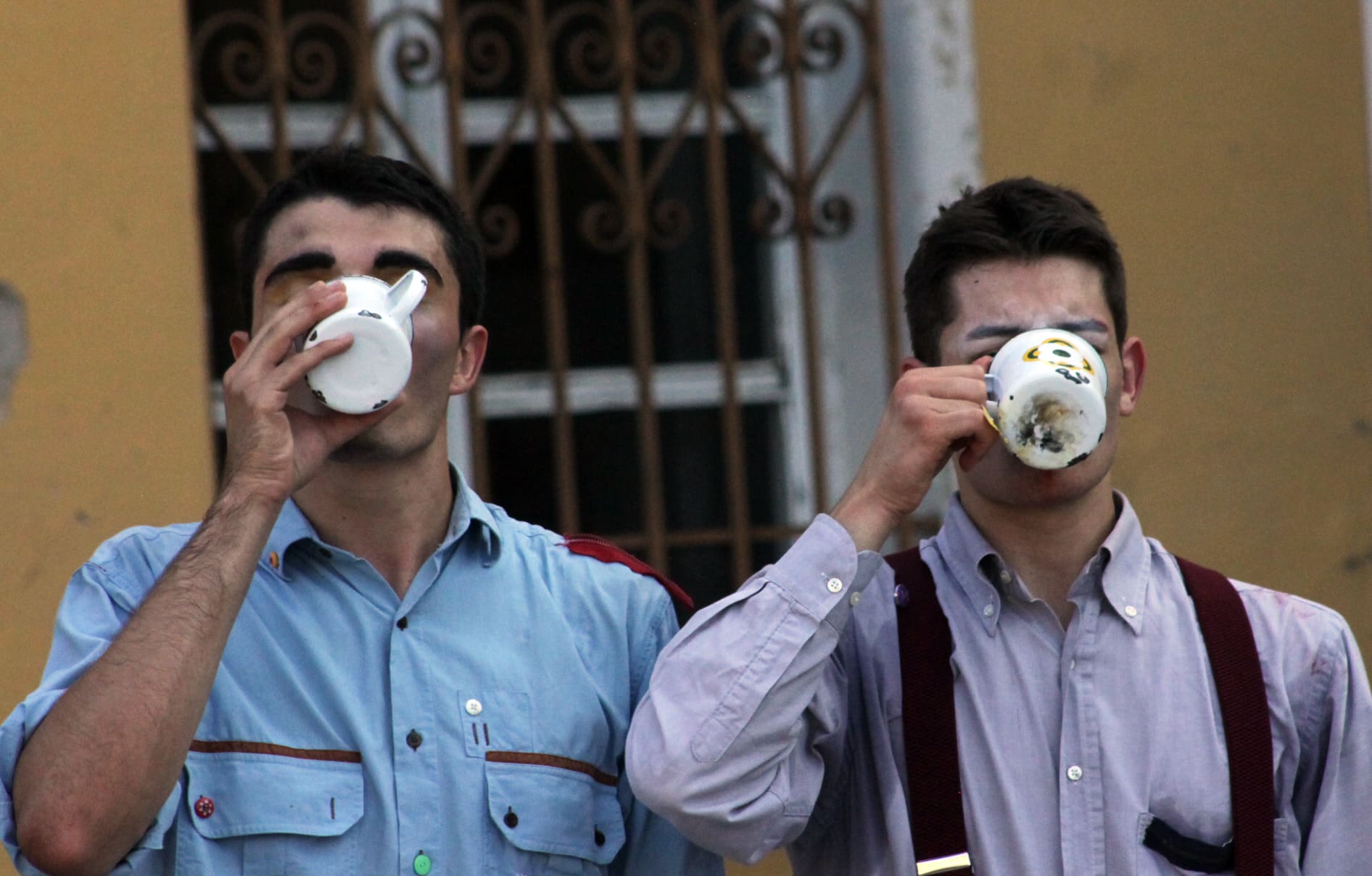 Due clown bevono fianco a fianco una tazza di tè.